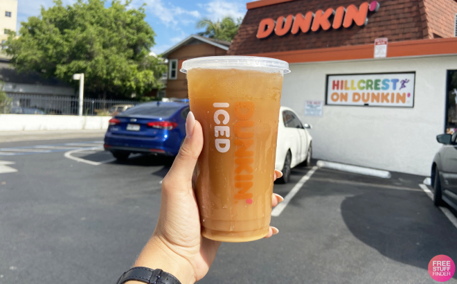 A Person Holding a Dunkin Coffee in Front of the Store A Person Holding a Dunkin Coffee in Front of the Store