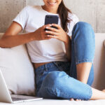A Person Sitting on a Bed and Looking at a Mobile Phone