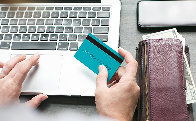 A Person Working on a Laptop while Holding a Card A Person Working on a Laptop while Holding a Card