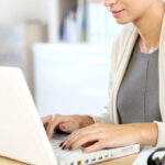 A Smiling Person Typing on a Laptop