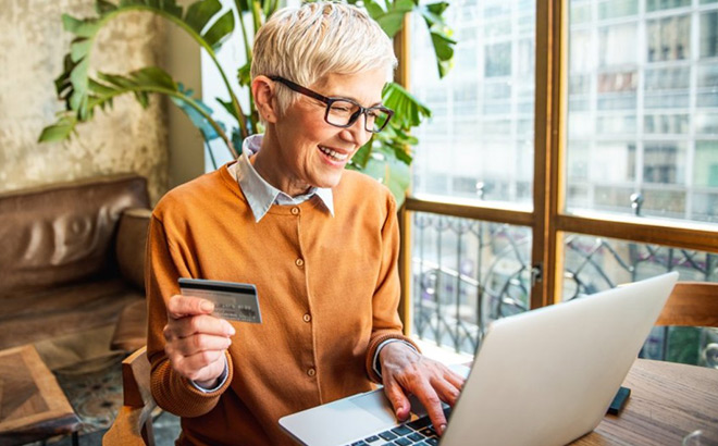 A Woman Smiling and Looking at the Laptop While Scoring Her AARP Membership