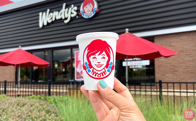 Hand holding Jr Frosty in front of Wendys Store Hand holding Jr Frosty in front of Wendys Store